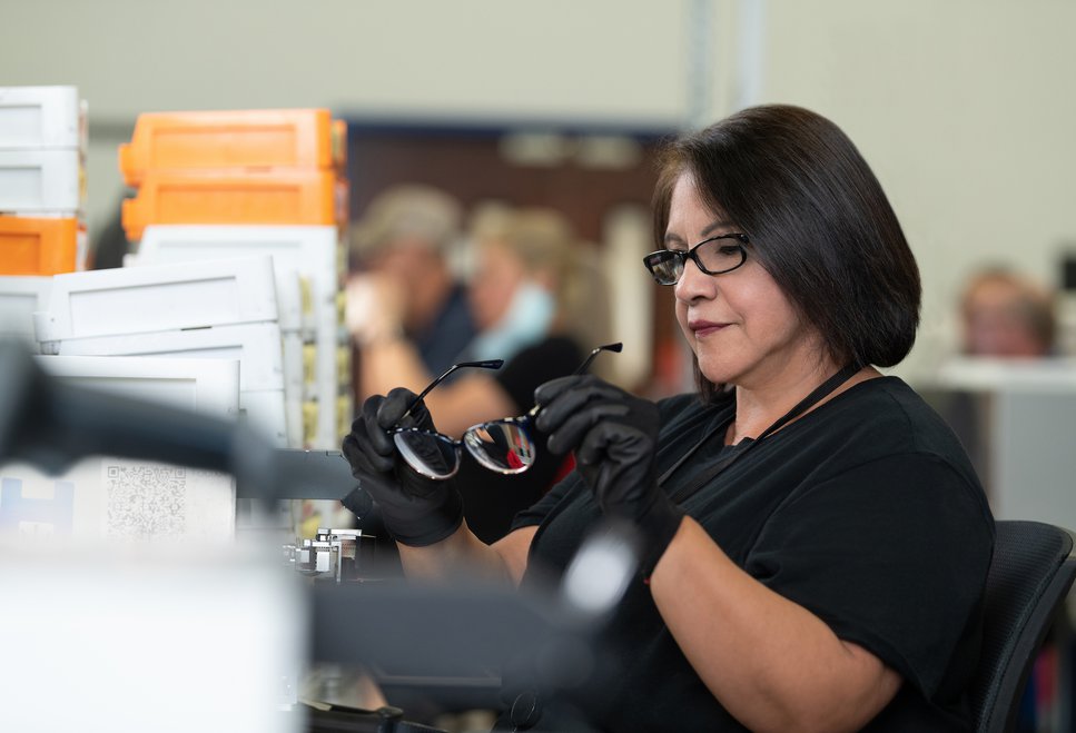 woman wearing gloves inspecting pair of glasses
