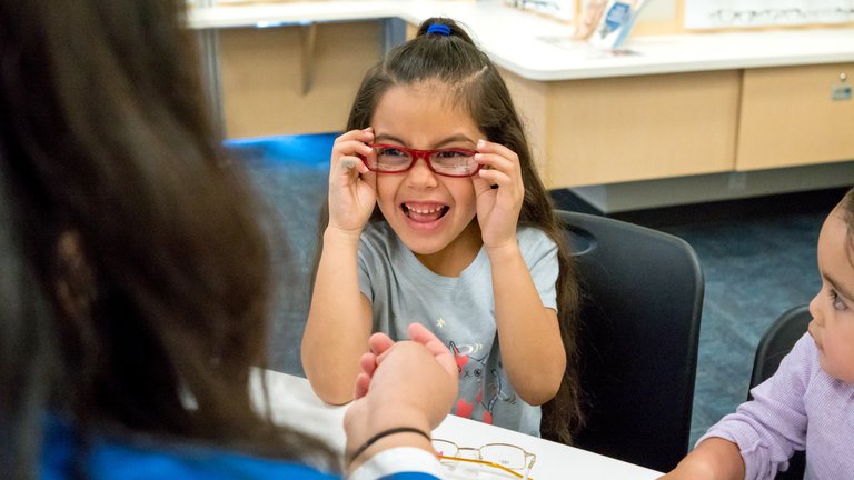 Child trying on eyeglasses and smiling