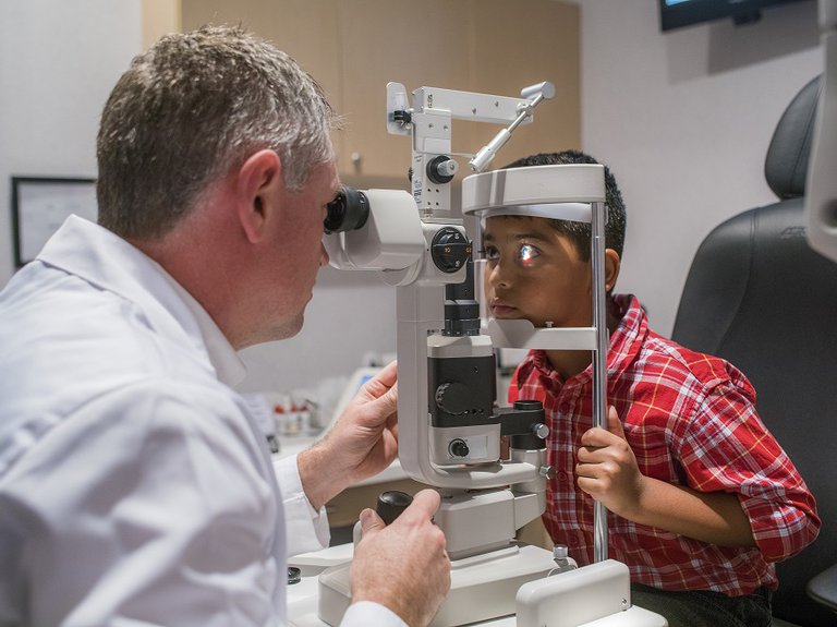 Male optometrist performing eye exam on child