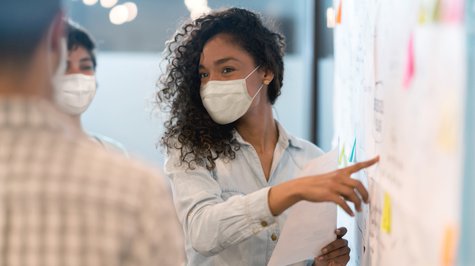 Woman in mask leading a work meeting