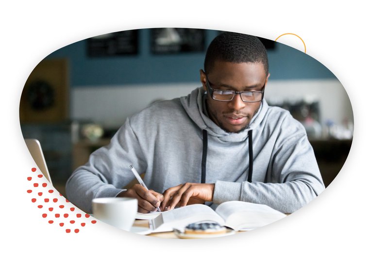 African American male wearing glasses and working on his studies at a coffee shop.