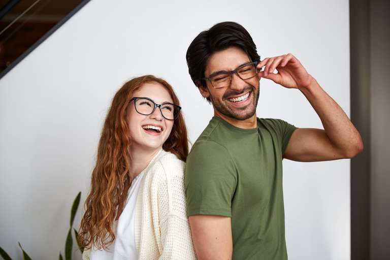 A man and a woman standing back to back wearing glasses