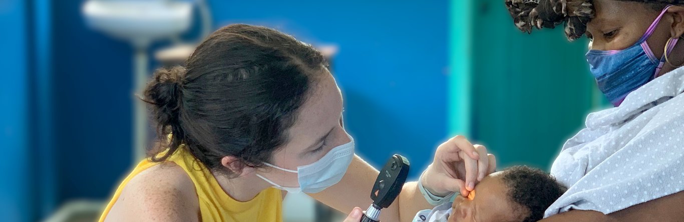 Woman using tool to look in infant's eyes