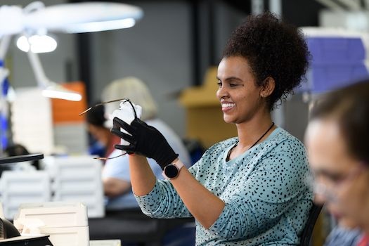 woman smiling while wiping glasses lens