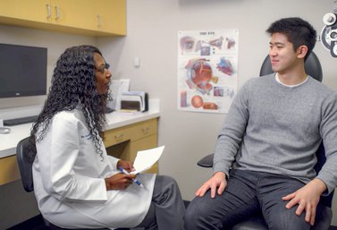 Young woman doctor talking to patient in exam room.