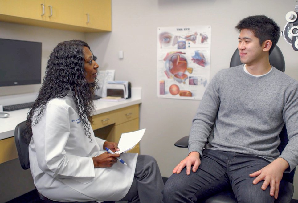 Young woman doctor talking to patient in exam room.
