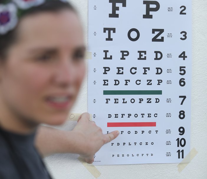 Young woman pointing a line on an eye chart