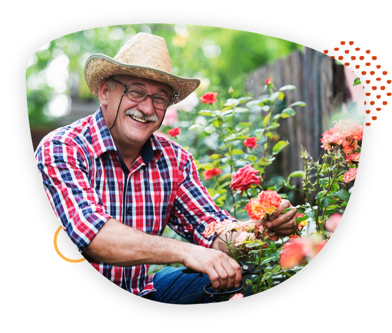 man in hat trimming a flower bush